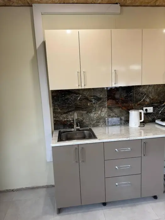 Kitchen counter with sink, kettle and hob under wall cupboards