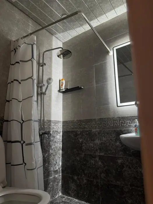 Bathroom with rain shower and lit mirror in daylight